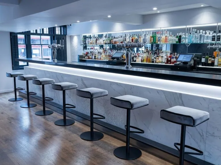 Commercial bar counter with backlit marble front and bar stools