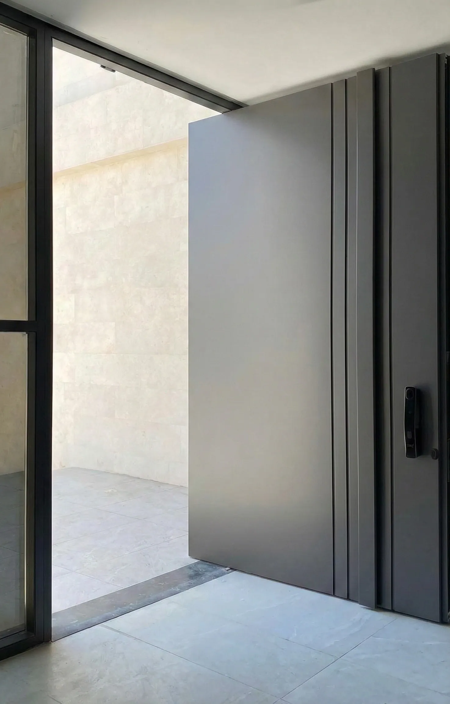 Grey flush pivot door open onto a stone entrance
