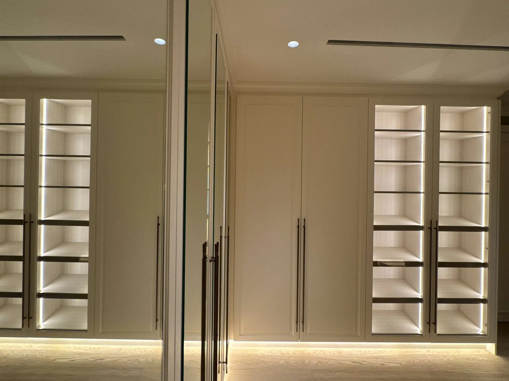 Built-in wardrobes with LED-lit open shelving and handleless cream doors