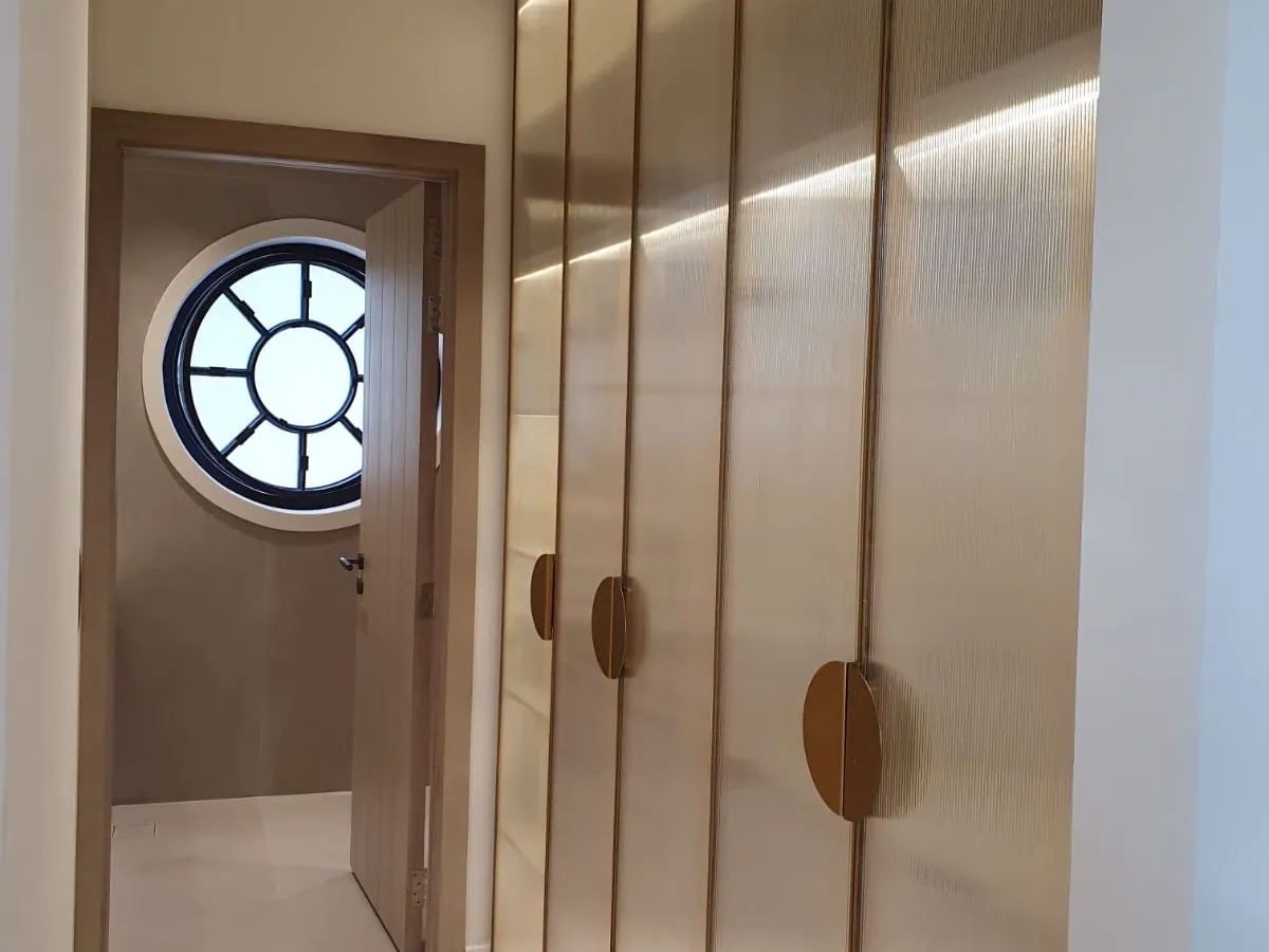 Cream lacquer wardrobe doors with bronze half-moon handles and inset lighting